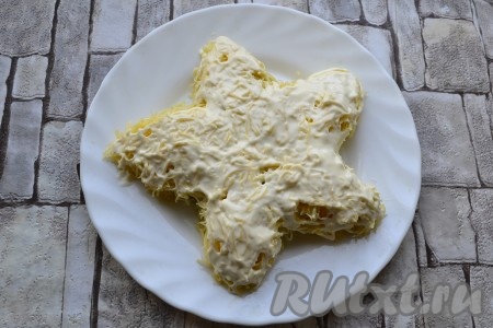 Смазать огуречный слой майонезом и покрыть весь салат слоем натертого на мелкой терке твердого сыра. Сыр тоже смазать майонезом.
