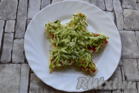 Далее идёт слой натертого на крупной терке и отжатого от жидкости свежего огурчика.
