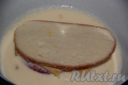 Окунуть кусочки батона с колбасой и сыром в яично-молочную массу с двух сторон.
