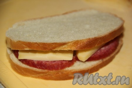 Сыр нарезать тонкими ломтиками. В каждый кармашек из батона вложить колбасу и сыр.
