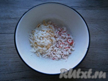 Оставить для украшения 4-5 крабовых палочек, остальные палочки нарезать. Рубленные вареные яйца добавить к нарезанным палочкам.
