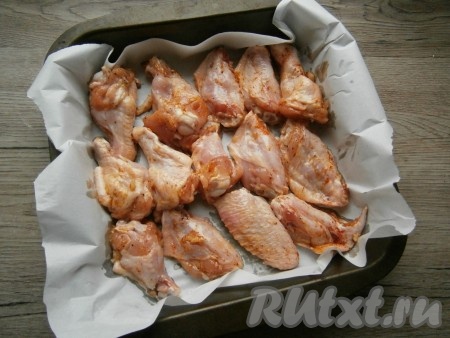 Форму для запекания или противень застелить пергаментом, выложить крылышки.
