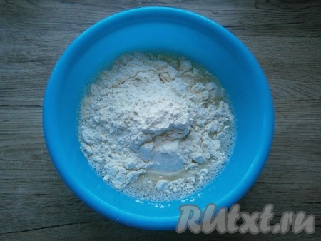 Частями всыпать муку, замешивая тесто.