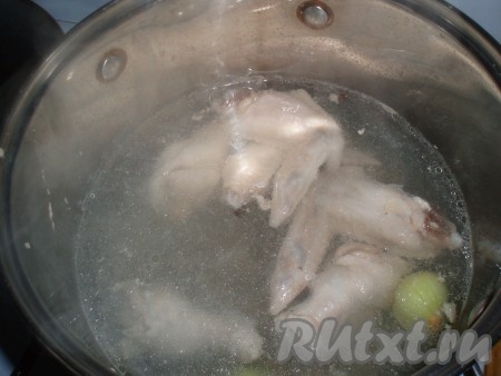 На сильном огне довести содержимое кастрюли до кипения. Снять образовавшуюся пену, уменьшить огонь до минимального, посолить по вкусу, добавить перец горошком и очищенную луковицу. Варить почти до полной готовности крылышек. Луковицу вынуть (она нам больше не понадобится).