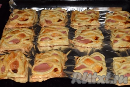 Отправить противень со слойками в разогретую духовку и выпекать при температуре 180 градусов, примерно, 30-35 минут. Когда тесто станет золотистым, вынуть слойки с колбасой и сыром из духовки и переложить на блюдо.
