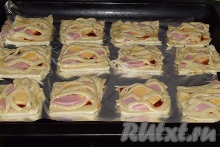 Слойки с колбасой и сыром выложить на противень, застеленный фольгой или пергаментом. Смазать яйцом каждую слоечку.