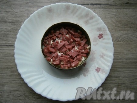Следующим слоем выложить нарезанную маленькими кубиками колбасу.
