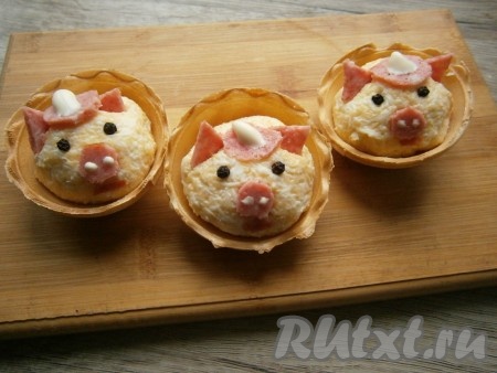 И далее оформить мордочки свинок: ушки, пятачок, ротик и шляпки вырезать из тонких ломтиков колбасы (шляпку и пятачок оформить точками из майонеза), глазки сделать из черного перца горошком.