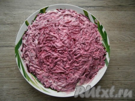 Последним слоем выложить очищенную вареную свеклу, натертую на крупной или средней терке, немного смазать майонезом.
