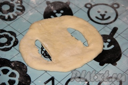 Обмять подошедшее тесто, прикрыть полотенцем и оставить на столе на 25 минут. Затем разделить тесто на равные кусочки. Каждый кусочек раскатать в круг (не тонко) на столе, припыленном мукой. На каждом кружке теста сделать два разреза по бокам (как на фото).
