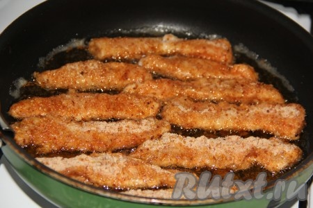 В сковороду влить столько растительного масла, чтобы было закрыто всё дно, разогреть. Выложить куриные стрипсы в панировочных сухарях в разогретое масло.