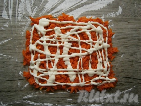 Расстелить на плоской поверхности пищевую пленку. Вареную морковь очистить и натереть на крупной, средней или мелкой терке, выложить квадратным или прямоугольным слоем на пленку, смазать майонезом.
