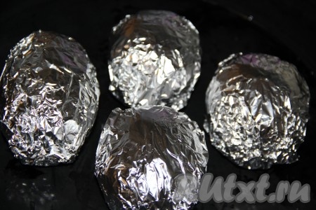 Каждую картофелину завернуть в фольгу и выложить на противень. Запекать картошку в разогретой духовке при температуре 200 градусов, примерно, 45-60 минут (продолжительность запекания зависит от размера картофеля). Готовность картошки можно проверить зубочисткой (зубочистка будет легко входить в готовый картофель).