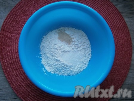 В миску просеять половину муки, добавить соль, сахар и сухие дрожжи, перемешать.