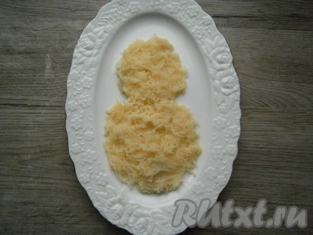 Картофель, яйца и курицу предварительно отварить. Для этого блюда можно взять не только вареное куриное филе, но и вареное мясо, срезанное с любых частей курицы. Вареный картофель очистить и натереть на мелкой терке, выложить его на овальную или прямоугольную тарелку в виде двух кругов (больший и меньший - туловище снеговика).
