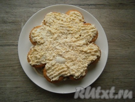 Затем снова выложить слой крекеров в таком же порядке и повторить слои: выложить 1/3 часть яично-сырной массы, сверху разместить оставшиеся рыбные консервы, выложить равномерно оставшийся лук, немного смазать майонезом. Покрыть третьим слоем крекеров, которые смазать оставшейся 1/3 частью сырно-яичной массы, разровнять.