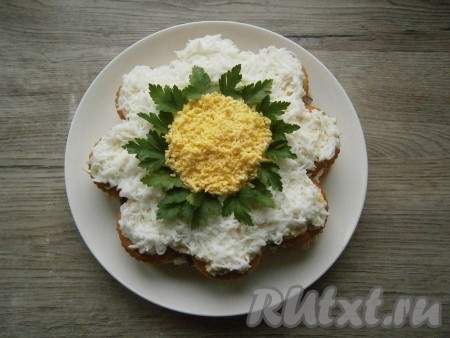 Оставшееся яйцо разделить на белок и желток, отдельно натереть белок и желток на мелкой терке. Желток выложить кругом в середине салата, а белком покрыть края, чтобы получился вид ромашки (как на фото). Украсить салат-торт зеленью петрушки.