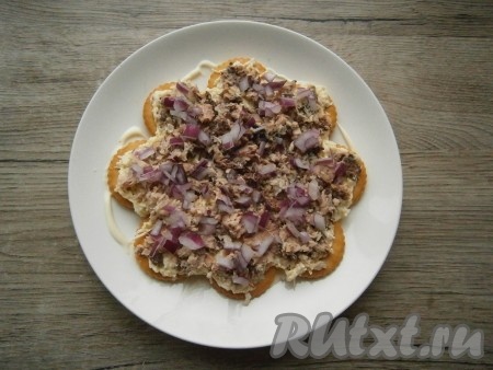 Далее выложить половину рыбы, на нее - половину очищенного и мелко нарезанного лука.
