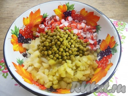 В глубокой миске соедините нарезанные огурчики, картофель, куриные яйца, крабовые палочки. Добавьте консервированный горошек без жидкости.
