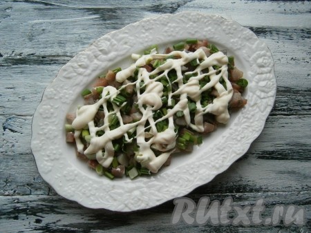 Нарезать селёдку на маленькие кусочки, выложить на блюдо первым слоем, посыпать большей частью мелко нарезанного зелёного лука (немного лука оставить для украшения), смазать слой майонезом.