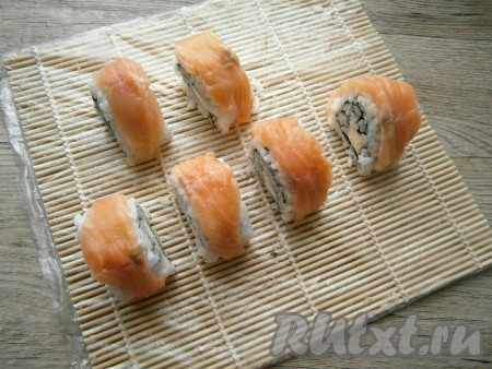 Покрыть каждый ролл сверху и с боков подготовленными тонкими длинными пластинами рыбы, чуть прижимая ее к рису.
