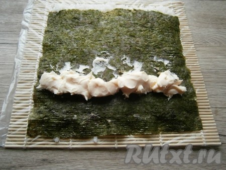 Затем ближе к нижнему краю нори во всю ширину выложить сливочный сыр (как на фото).
