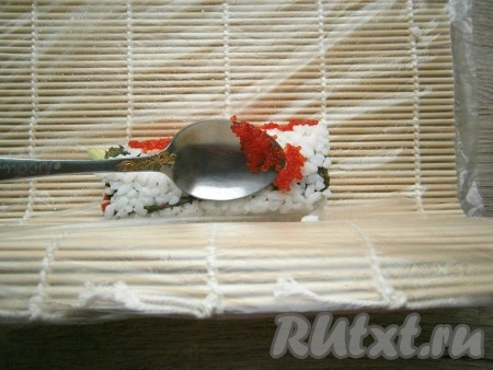 Прокручивая половинку ролла циновкой, с помощью ложки обсыпать ролл со всех сторон тонким слоем (немного придавливая) икры тобико (летучей рыбы).