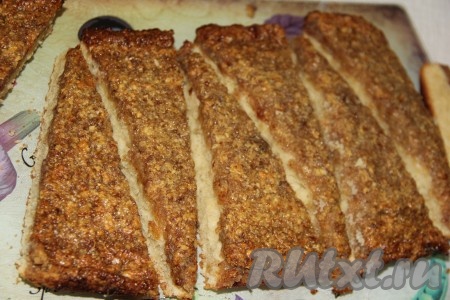 Готовый корж слегка остудить и достать на пергаменте. Снять корж с пергамента и разрезать на высокие треугольники, по форме напоминающие ёлочки.
