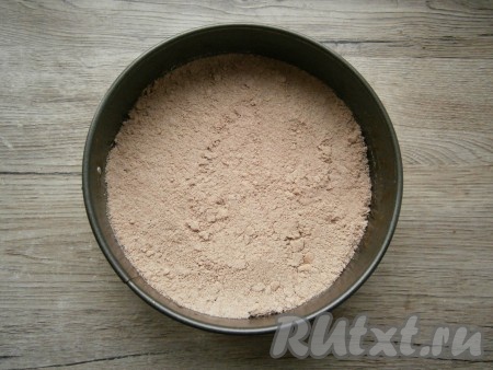 Дно разъёмной формы диаметром 18-19 сантиметров застелить пергаментом, насыпать 2/3 шоколадной крошки, разровнять, чуть утрамбовать.