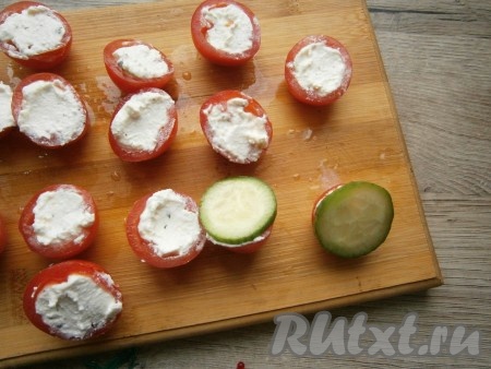 На часть половинок фаршированных помидоров выложить по тонкому кружочку свежего огурчика.
