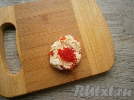 Аккуратно массу перемешать и сформировать 4 шарика размером с грецкий орех и, размяв каждый шарик в лепешку, в середину поместить по 0,5 чайной ложки любой мелкой икры - тобико, мойвы, минтая и т.д. Получится 4 сырных шарика с икрой.

