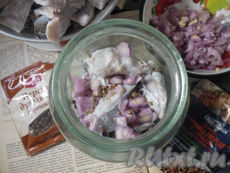 Затем, чередуя кусочки толстолобика с луком, специями и лавровыми листьями, выкладывайте их в банку.
