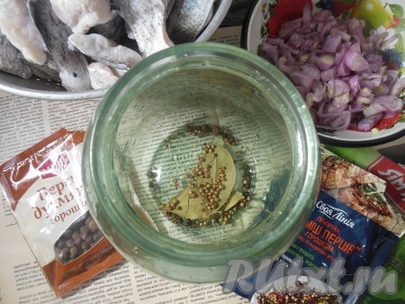Отдельно нарежьте очищенный репчатый лук. На дно 1,5-литровой банки поместите лавровый лист, немного кориандра, смеси перцев горошком и горошин душистого перца (не выкладывайте много специй на дно банки, лавровые листья и специи мы будем чередовать с рыбой).
