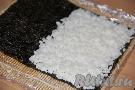 Я готовила роллы на целом листе нори. Роллы хорошо завернулись и получились не маленькими.&nbsp;На подготовленную циновку выложить лист нори блестящей стороной вниз. На 2/3 листа нори равномерно распределить небольшое количество риса, 1/3 часть листа нори оставить свободным (как на фото).
