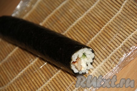 Плотно завернуть начинку в лист нори, начиная с края листа нори с рисом. Краешек листа нори, на который не выкладывался рис, смазать водичкой, он хорошо и плотно склеится, поэтому ролл с курицей, огурцом и сыром получится плотненьким и красивым.
