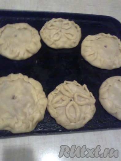 В центре каждого порционного курника делаем дырочку для выхода пара. Выкладываем пироги на слегка смазанный растительным маслом противень.
