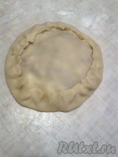 Смачивая края меньшей лепешки водой, приклеиваем их к основе курника (или плотно прижимаем). Собираем равномерно свободные края большей лепешки и, подтягивая края теста к верху и слегка защипывая,&nbsp;прижимаем к меньшей лепешке, формируя курник, как на фото. Таким же образом формируем курники из оставшихся 5 частей теста. В результате получится 6 курников.
