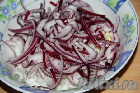Лук очистить, нарезать на тонкие полукольца и выложить к кальмарам.
