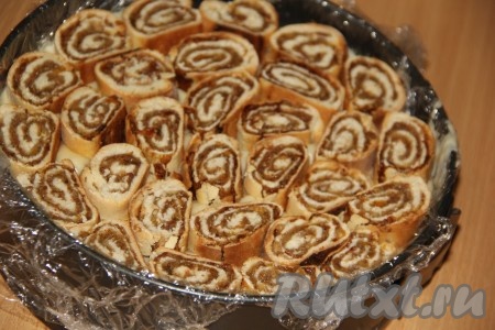 Хорошо смазать слой рулетов кремом, а затем выложить слой рулетов с изюмом и орехами.
