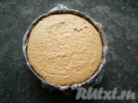 Набухший желатин прогреть, помешивая, на водяной бане или в микроволновке, не доводя до кипения. Я предпочитаю прогревать желатин в микроволновке, для этого ёмкость с набухшим желатином ставлю в микроволновку на максимальную мощность на 10 секунд, перемешиваю, если кристаллики желатина ещё растворились не все, тогда прогреваю в микроволновке ещё в течение 10 секунд. Очень важно, чтобы желатин полностью растворился, но при это не закипел. Остудить немного прогревшуюся желатиновую массу. Интенсивно перемешивая смесь творога и варёной сгущёнки, влить в неё желатиновую массу, тщательно перемешать. Достать из холодильника форму с печеньем и выложить в неё творожно-желатиновую массу, разровнять. Отправить форму в холодильник на 3-5 часов (до полного застывания  творожно-желатиновой массы).