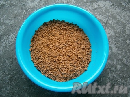 Измельчить печенье до состояния крошки, затем пересыпать в миску. Если нет блендера, можно поместить печенье в целлофановый пакет, завязать пакет и прокатать поверх пакета скалкой, измельчая печенье в крошку.