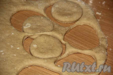 Готовое тесто на столе, присыпанном мукой, раскатать скалкой в пласт толщиной, примерно, 1-1,5 см. С помощью стакана вырезать кружочки из теста.
