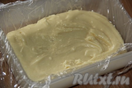 Пластиковый контейнер застелить пищевой плёнкой. Выложить массу в контейнер и равномерно распределить.