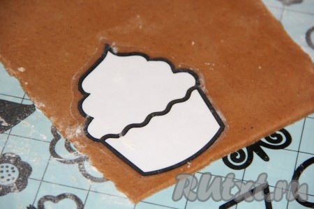 Слегка припылить поверхность стола (или силиконового коврика) мукой, раскатать тесто скалкой. Толщина раскатанного теста должна быть, примерно, 0,5 см. С помощью вырубки для печенья вырезать пряники нужной формы. Я вырезала пряники ножом по трафарету. 
