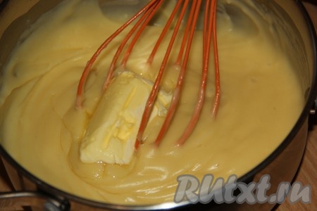 Кастрюлю с кремом снять с огня и добавить сливочное масло. Перемешать крем до полного растворения масла.
