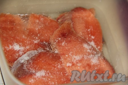 На дно пластикового контейнера влить растительное масло. Выложить ломтики горбуши и слегка присолить.
