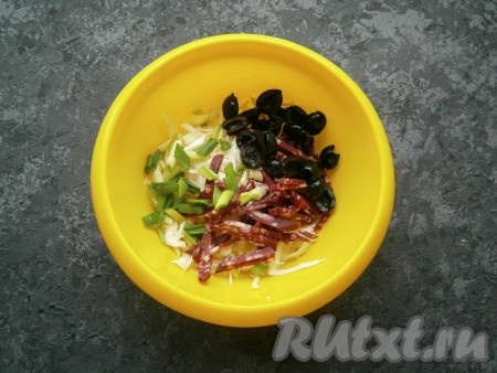 Оливки разрезать на 2 части, добавить их в салат вместе с измельченным зеленым луком.
