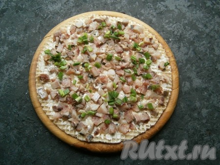 Выложить по всему коржу половину селедки, посыпать половиной измельченного зеленого лука.