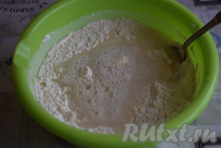 В смеси муки и дрожжей сделаем углубление, в которое всыпем сахар, соль и вольем теплую воду (температура воды не должна превышать 40 градусов), перемешаем тесто ложкой.
