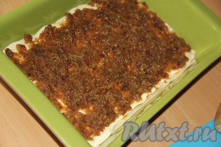 Накрыть курагу вторым слоем раскатанного теста. Поверх теста выложить всю массу из изюма и равномерно распределить. Присыпать изюм 1/3 сахара.